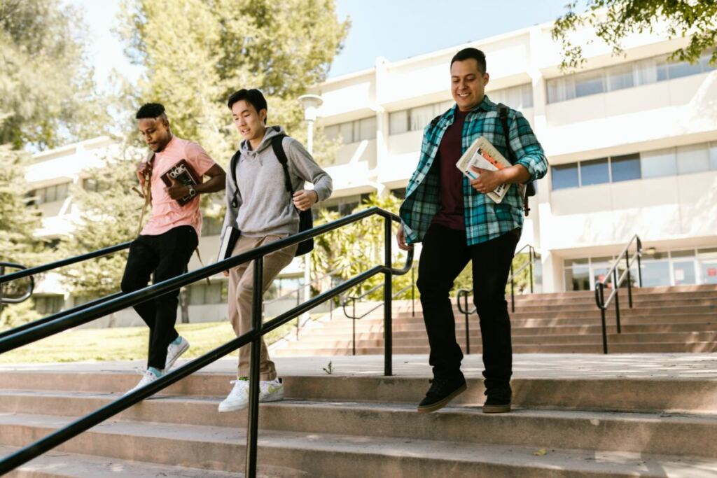 Three college students outside walking down steps.