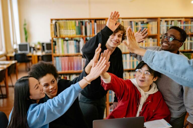 A group of students high-fiving over the table